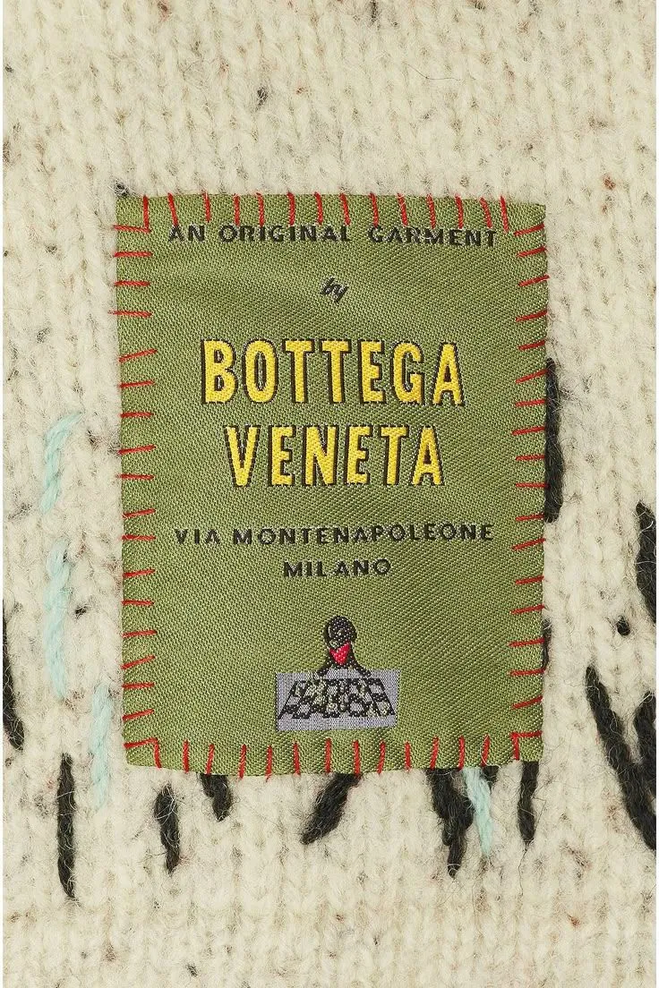 Bottega Veneta green woven label with red stitching on hand knit.
