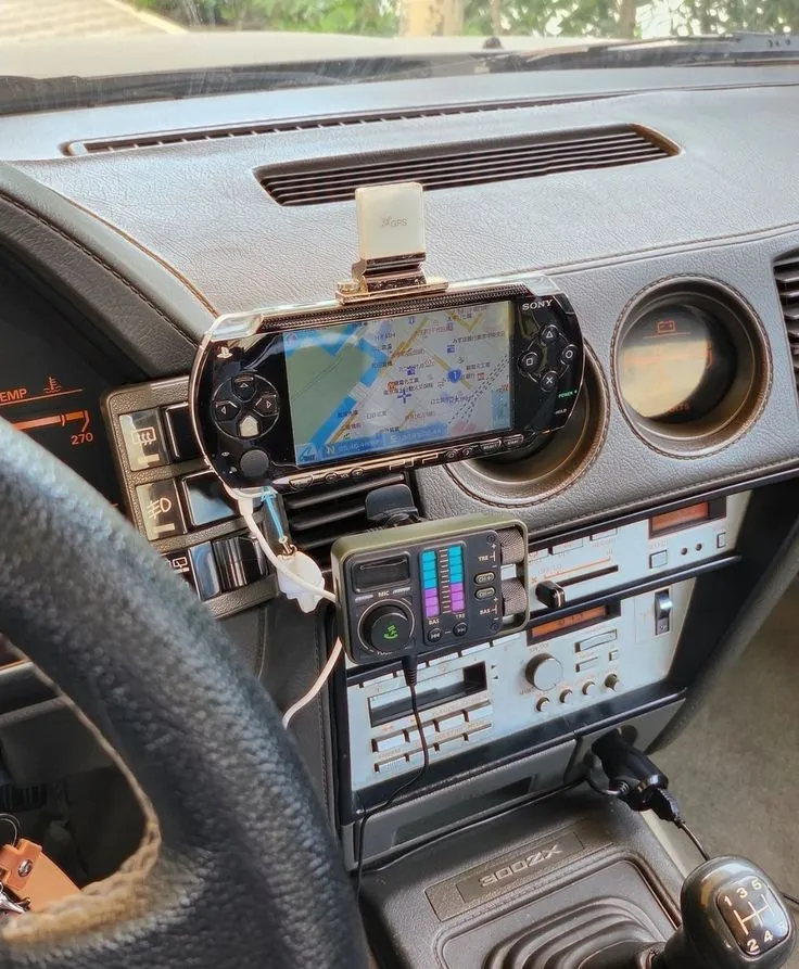 A PSP mounted on a car dashboard showing a Japanese map navigation screen, with 300ZX badging visible on the shifter surround and an aftermarket audio unit below it.