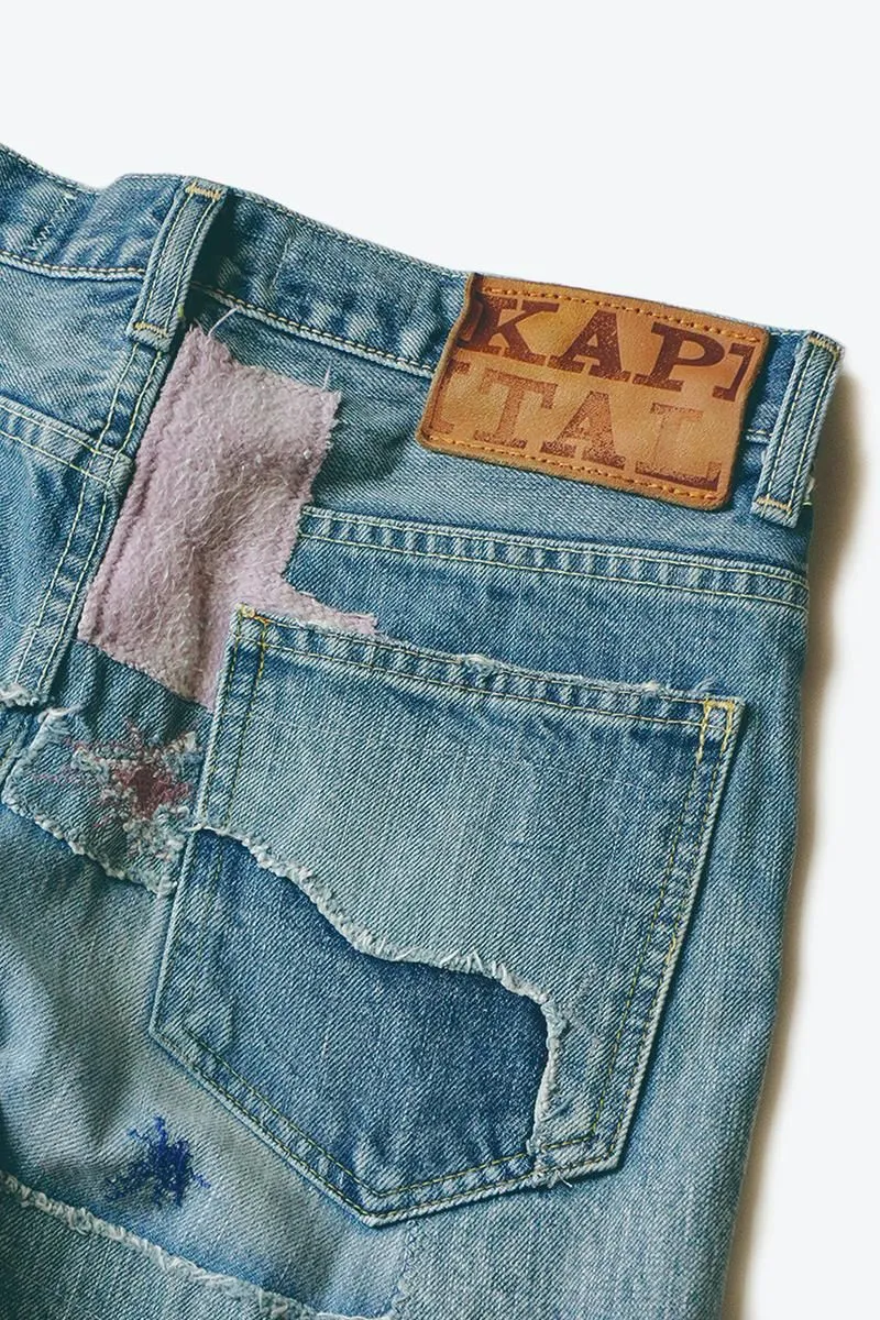Washed and heavily repaired Kapital jeans, showing a tan leather patch above a torn and patched back pocket.