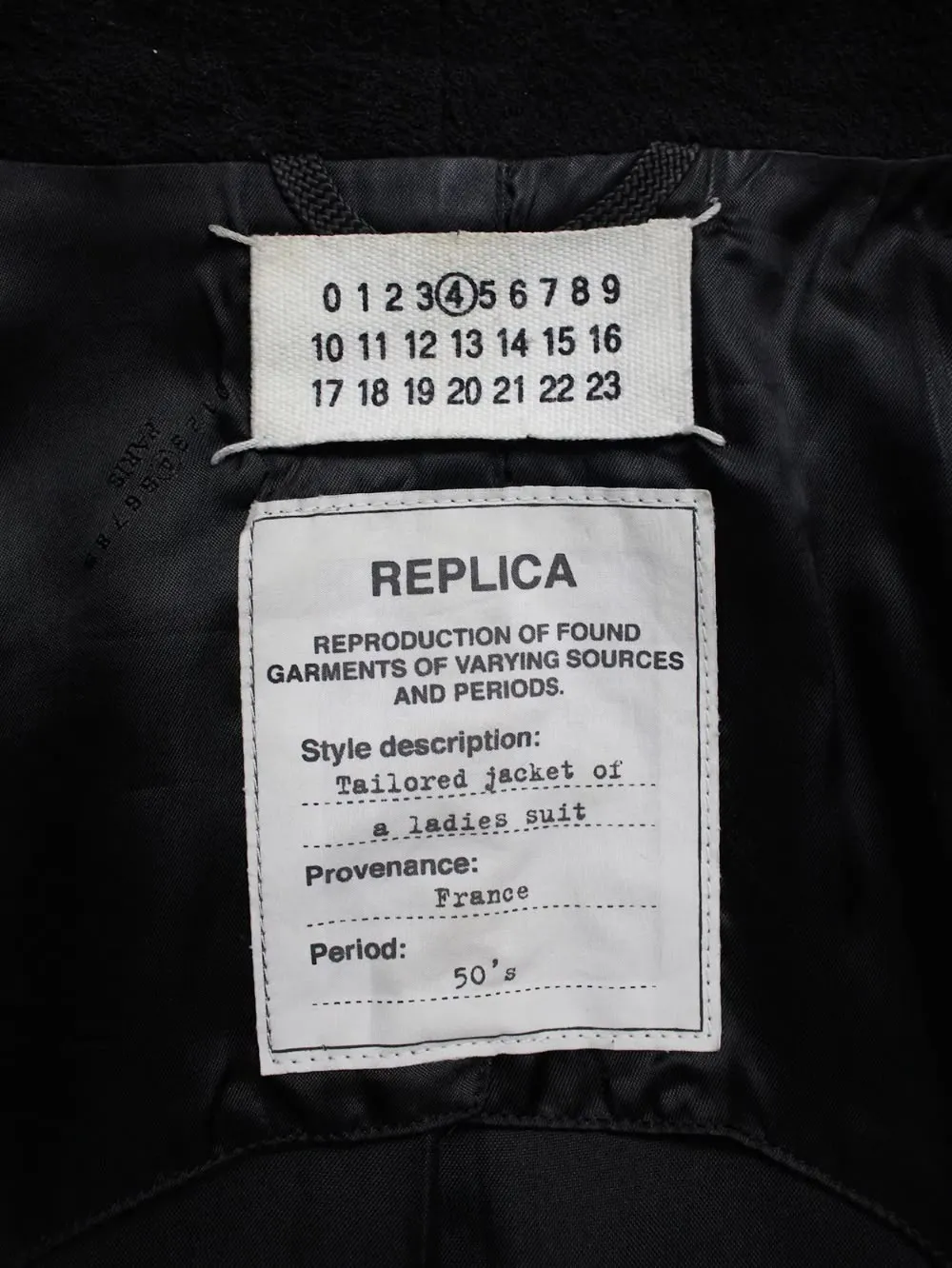 Margiela Replica tag on a tailored jacket, alongside the numerical tag with 4 circled.