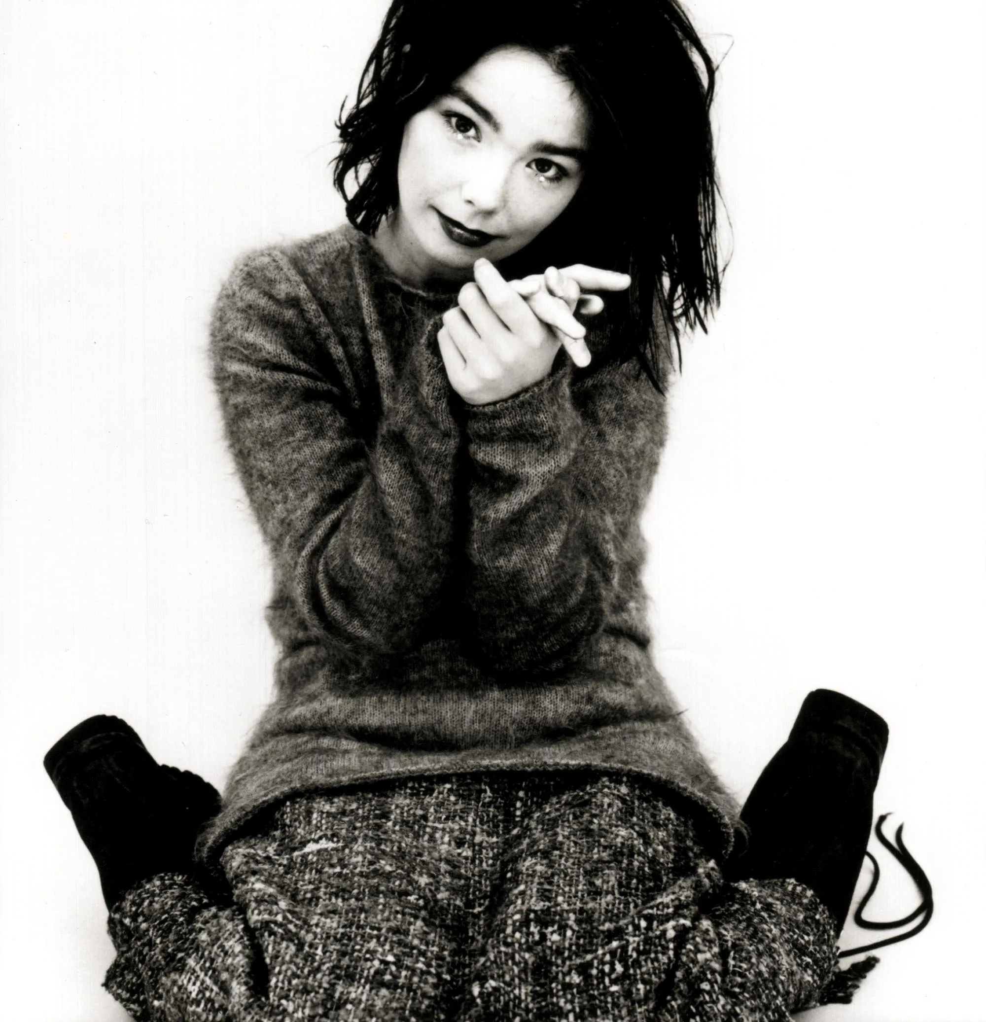 Black and white photograph of Björk in a mohair sweater, one hand raised near her chin, from the same 1993 session.