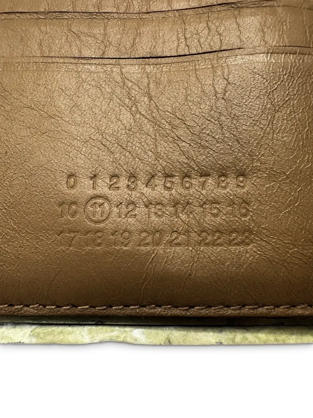 A macro close-up of the wallet's leather interior, stamped with the numbers 0 through 22 in a row, with the number 11 circled.
