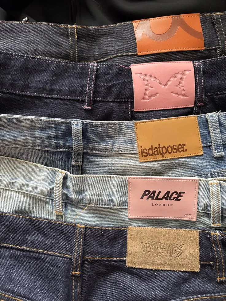 Five pairs of jeans stacked to show their leather patches side by side.