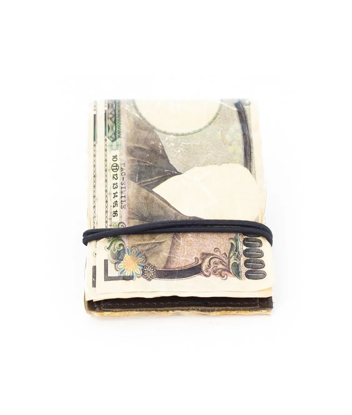 A worn leather wallet wrapped in a fake Japanese 10000 yen note, bound shut with a black elastic band.